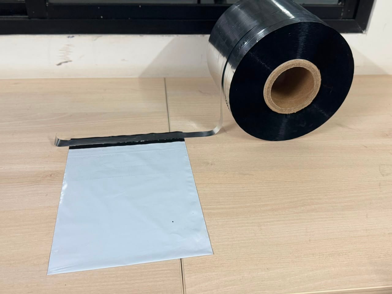 A reel of silicone-coated metallised release film with the film running out onto the sealed flap of a white courier mailer